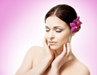 Naklejka premium Beautiful face of a young and healthy girl with an orchid flower