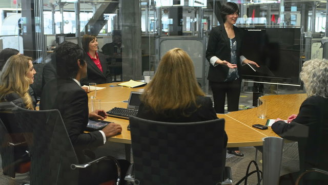 An attractive young businesswoman gives a presentation in a conference room to her well-dressed team