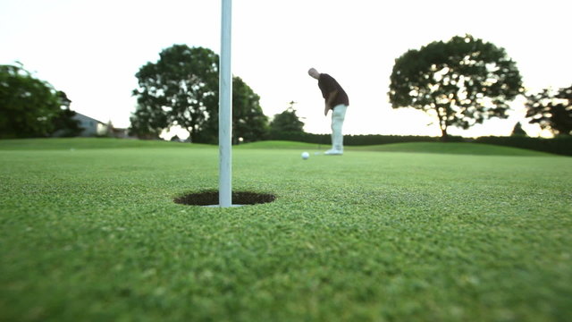 Wide shot of golfer attempting a long putt and almost makes it