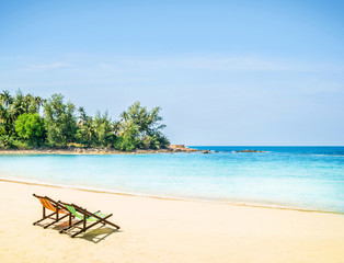Fototapeta na wymiar Lounge chairs on a tropical beach at summer