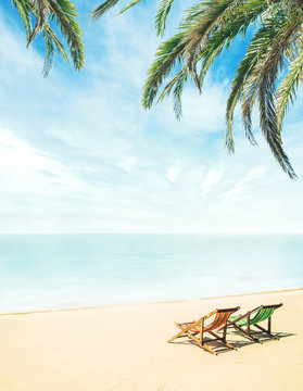 Fototapeta Lounge chairs on a tropical beach at summer