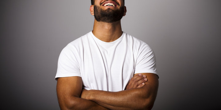 Hombre joven con barba y camiseta blanca con brazos cruzados