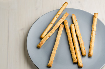 rustic breadsticks in a dish on wood table, close up, background