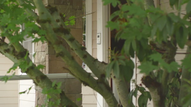 Two Young Girls Run Up And Open The Front Door To Their House, As Seen From Behind A Tree. Voyeuristic