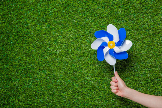 Hand Holding Pinwheel Over Grass