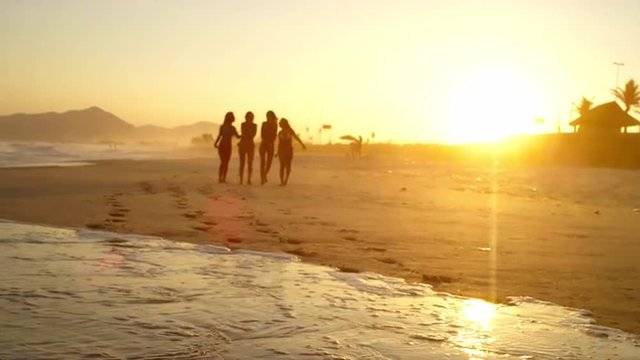 Young Brazilian women walk down a beach in Brazil