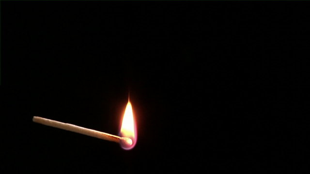 Footage of a match igniting and burning as it rotates.