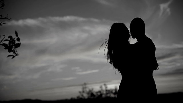 A silhouette of a couple kissing on black and white