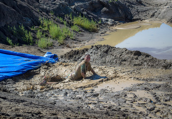 Mud Run CO.large blue slide face first into muddy water
