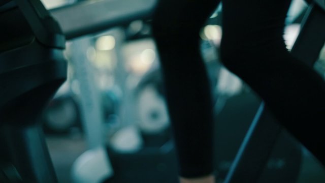 Legs of woman as she works out on Elliptical machine at gym