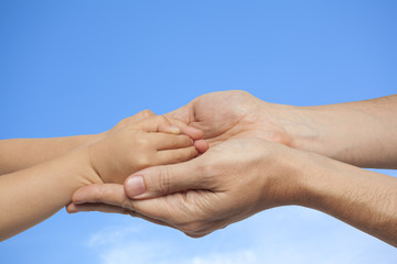 father and son holding hands on sky background