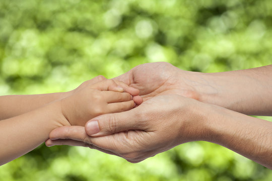 father and son holding hands on natural background