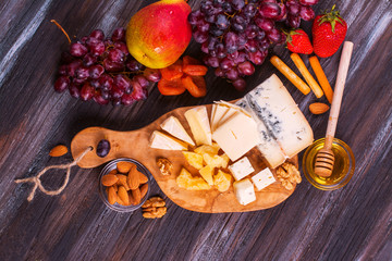 Different types of cheese with fruits, berries, honey and nuts