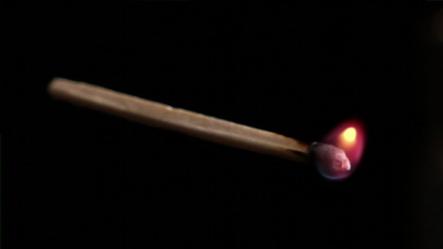 Close up of a burning match isolated on a black background