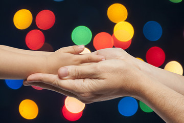 father and son holding hands on christmas lights background