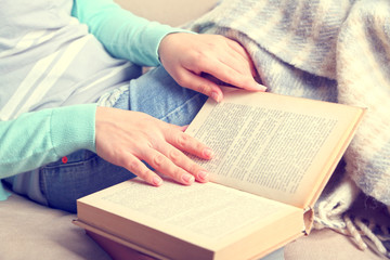 Young woman reading book at home, close-up