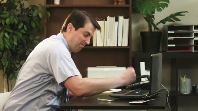 An angry businessman punches his computer. Slow motion