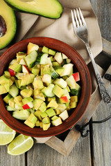Salad with apple and avocado in bowl on tray on table close up