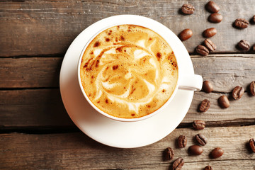 Cup of coffee latte art with grains on wooden background