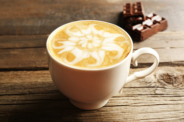 Cup of coffee latte art with chocolate on wooden background