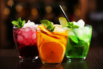 Glasses of cocktails on bar background