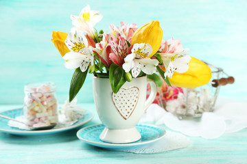 Beautiful flowers in cup, on color wooden background