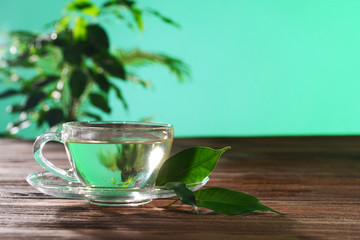 Cup of green tea on table on green background