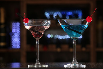 Glasses of cocktails on bar background