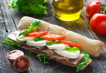 Sandwich with crispy baguette on a wooden background