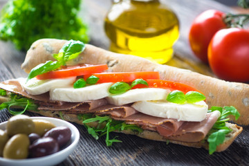 Sandwich with crispy baguette on a wooden background