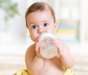 cute baby holding bottle and drinking water