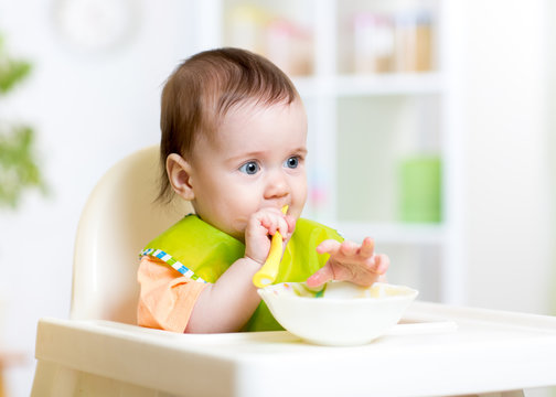 happy baby child sitting in chair with a spoon