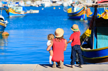 Fototapeta na wymiar mother and kids looking at traditional boats in Malta