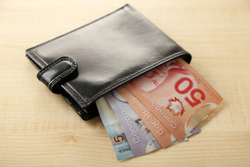 Male wallet with Canadian dollars on wooden table