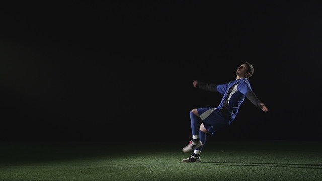 Soccer player jumps in the air sideways and kicks a soccer ball