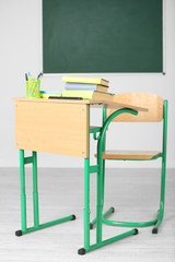 Wooden desk with stationery and chair in class 