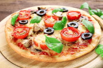 Tasty pizza with vegetables and basil on table close up