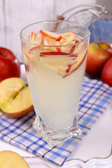 Glass of apple cider with fruits on table close up