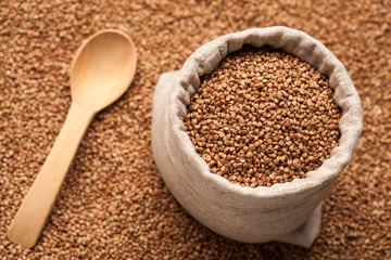 Buckwheat in linen sack with wooden spoon.