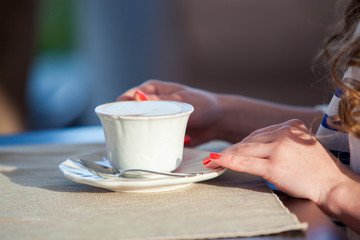 beautiful young girl in outdoor cafe reading a book and drinking
