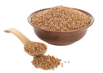 Buckwheat in bowl with wooden spoon on white.