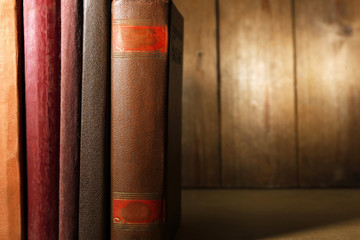 Old books on shelf, close-up, on dark wooden background
