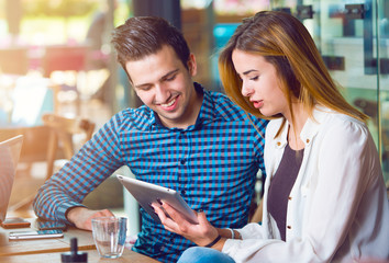 Fototapeta premium Two young people, man and woman, looking at a tablet