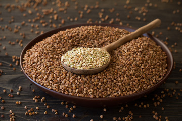 Green and brown buckwheat in ceramic bowl on a wooden surface
