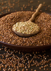 Green and brown buckwheat in ceramic bowl on a wooden surface