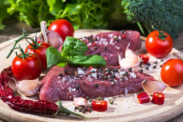 Raw beef steak with spices on a wooden board