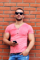 handsome young guy in sunglasses listens to music from player
