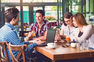 Group of young people sitting at a cafe, talking and enjoying