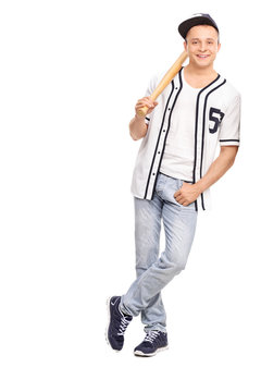 Young athlete holding baseball bat and leaning on a wall