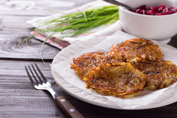 Potato fritters, beet salad, green onions on a wooden surface